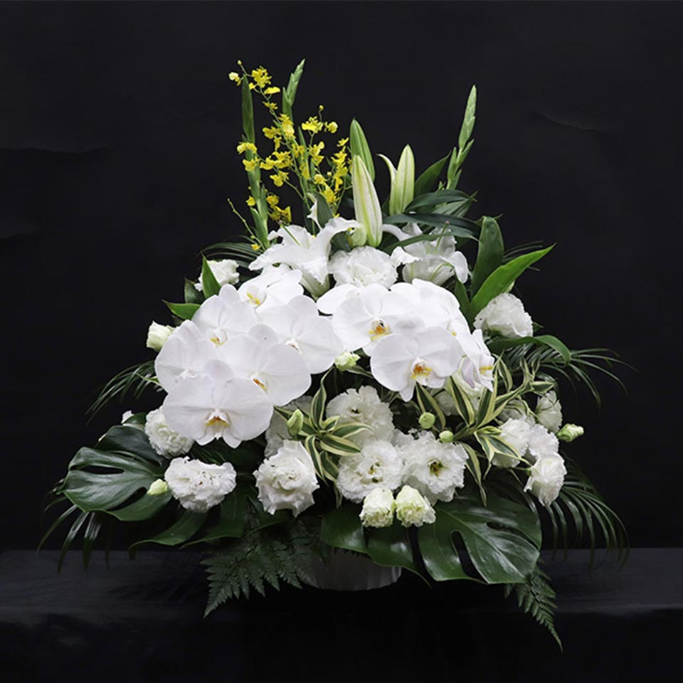 白い胡蝶蘭を中心に、白い花と緑の葉をあしらった枕花